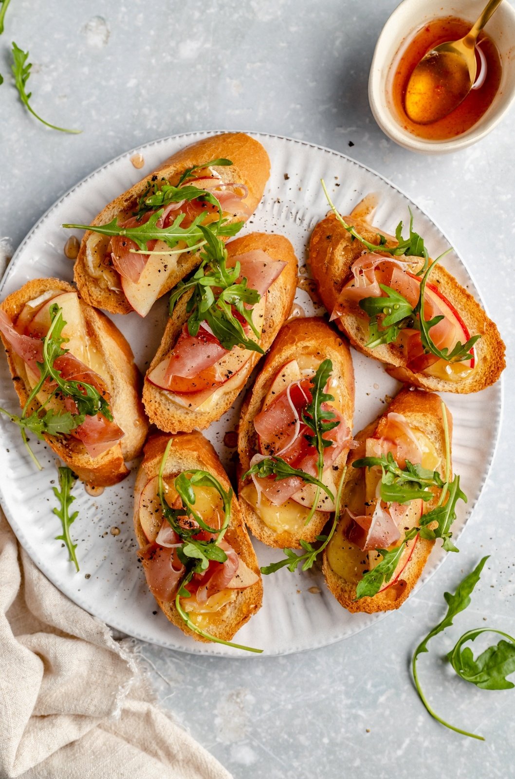 apple and brie crostini with prosciutto on a plate