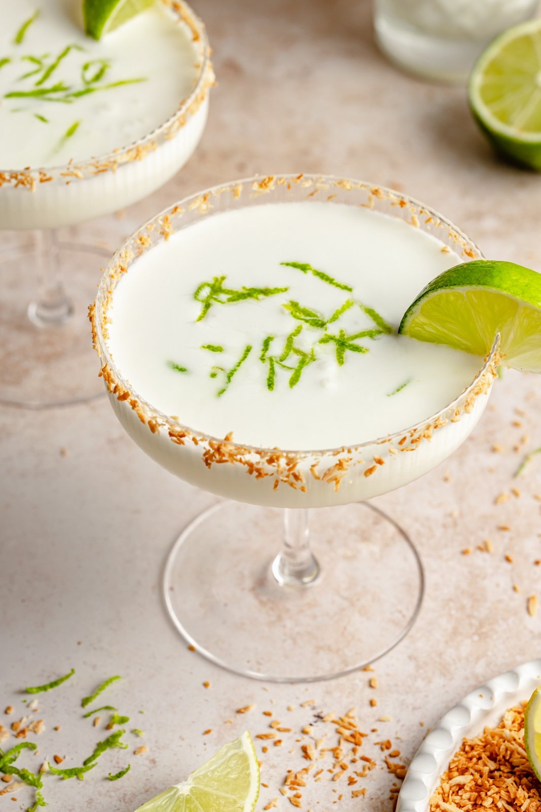 coconut margarita in a glass with a lime wedge